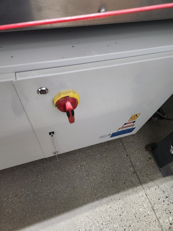 A red switch in an up-and-down position on the back of a Compac line machine.